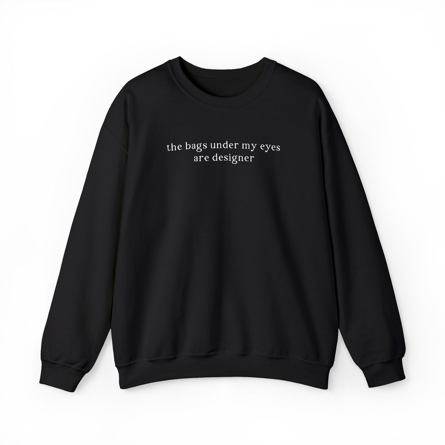 A black oversized sweatshirt featuring minimalist white text across the chest that reads 'the bags under my eyes are designer'. Clean studio product photography on a white background for the Barely Sane clothing collection.