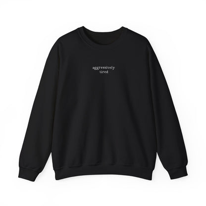 A black oversized sweatshirt featuring minimalist white text across the chest that reads 'aggressively tired'. Clean studio product photography on a white background for the Barely Sane clothing collection.