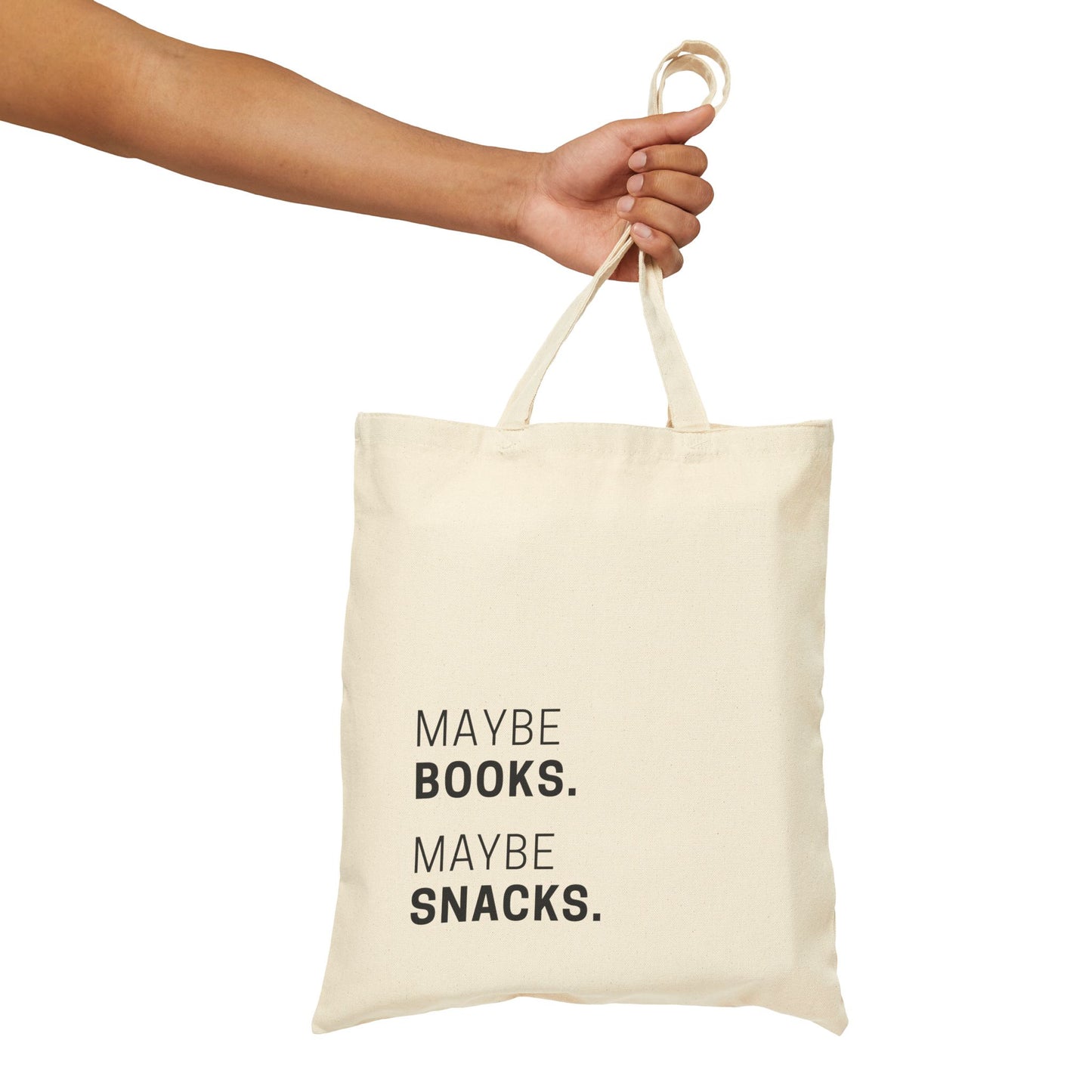 A hand holding 'The Maybe Books. Maybe Snacks.' tote bag in natural cotton canvas. Minimalist typography design on a clean, isolated background for Barely Sane's aesthetic parenting collection.